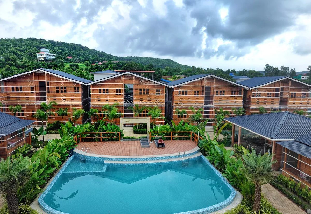 The Clouds Hotel & Resort, with timber-clad cottages around a central pool against the Konkan hillside